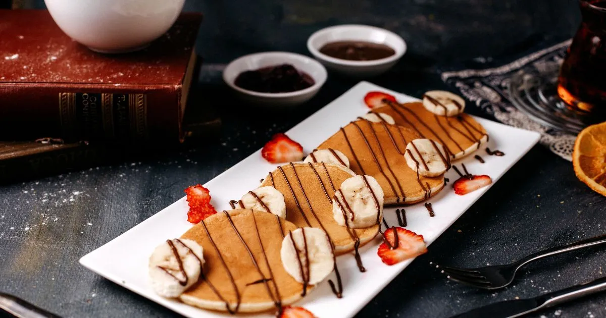 A stack of eggless pancakes with a drizzle of maple syrup and fresh fruit, showcasing a simple, egg-free breakfast